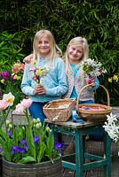 Mother's day posie step by step in April. Two sisters with posies of freshly picked garden flowers - pink Clematis armandii 'Apple Blossom', white amelanchier, daffodils, grape hyacinths, snowflakes, hellebores, lungwort, pear blossom and pink tulips.