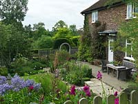 1930s cottage overlooks top garden, separated from lower garden by moongate and yew arch. Beds of aster, dahlia, gaura, box, hardy geranium, rose, verbena, salvia, sedum.