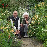 Bob and Shirley Stoneley sit between cottage garden style beds of perennials in their steeply sloping, fifth-of-an-acre garden set against a backdrop of Surrey hills.