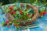 Secateurs, Wreath base and Ilex aquifolium - Common Holly cuttings, on a wooden table. 