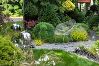View of the mirror, modern wrought armchair, sphere stainless steel water feature with LED lights and the path leading to the roof garden. Picea omorika, topiary - Taxus baccata and Buxus sempervirens 