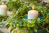 A wreath made of Mistletoe, Moss and Yew, used to decorate a candle holder. 