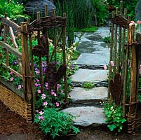 Woven willow gate opens onto path of reclaimed Cumbrian slate flagstones.