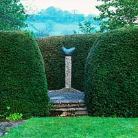 A triangle of tall, rounded yew hedges surround Bridget McCrum's 'Cycladic Dove', glimpsed through narrow gap.