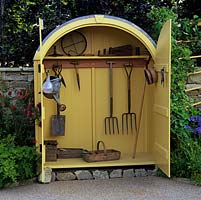 Free-standing wooden tool shed creates eye-catching feature in garden.