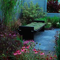 Aromatic thyme seat in tranquil courtyard. Slate patio edged by beds of nigella, echinacea, dogwood, liatris, echinops, black elder and bamboo.