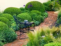 Brick paths separate beds of variously sized box balls with allium, Stipa tenuissima, lavender, rosemary, thyme and alchemilla.