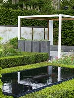 Pergola-like wooden frames focus attention on views within the space. Geometric layout of box and hornbeam mixes with perennials and shrubs. Pool edged in box. Pots of succulents.