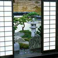 Doors slide back on verandah to reveal tiny courtyard garden in the restrained tsubo niwa style. Maple, rocks, moss and stone create serene ambience.