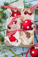 Red polkadot baubles in cardboard packaging, with larch foliage