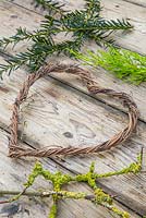 Twined heart wreath made from vines, with foliage of Conifer and Prunus with lichen