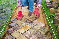 Arrange the bricks to form transverse chevrons in the desired direction of travel. Building a brick path