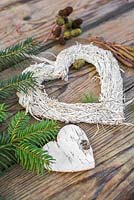 A white heart on a wooden surface, accompanied with a Birch heart, Pine foliage, Alder cones and Catkins