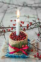 Candle mounted in a woven basket containing Crataegus - Hawthorn berries