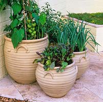 Three matching, curved unglazed clay pots filled with vegetables - onions, beetroot and tomatoes.