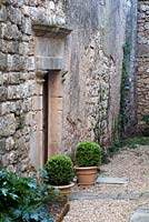 Stone courtyard with box balls in earthenware flowerpots. Domaine de Chatelus de Vialar.