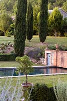 View across classically designed swimming pool using cool dark tiling to blend into landscape. Cupressus sempervirens 'Stricta' providing strong structural focus. 