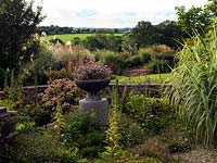 The Millennium Garden at Burrow Hill with pink Diascia in handcrafted bowl made from shards of slate, standing on upturned granite roller.