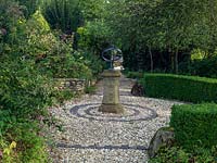 An ornamental sundial in the centre of a round gravel bed in the Terraced Garden.