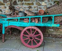 A colourful painted hand cart filled with gardening paraphernalia.
