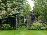 Acer negundo Flamingo, ash-leaved maple, overhangs statue in circle of box. Path edged in swags with roses. Beds: pink phlox, hardy geranium and Sedum Autumn Joy.