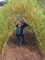 Brothers Jacob and Louis standing in the doorway of a tunnel woven from living Salix viminalis - willow.