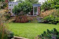 Oval shaped lawn in a split level terraced garden. 