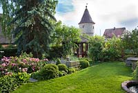 View of the garden backed with tower. lawn, topiary, summerhouse, pond, Rose 'Constance Spry'. Marina Wust, Germany
