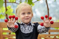 Young girl with raspberries on her fingers 
