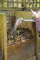 Watering dry material on compost heap.