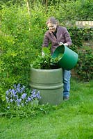 Woman adding green plant material to a compost bin