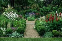 Formal garden with blue painted wrought iron bench, old sundial, gravel paths, herbaceous perennials  