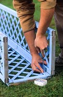 Man screwing blue painted trellis panels together
