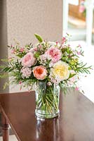 A cut flower arrangement with roses on a side table indoors