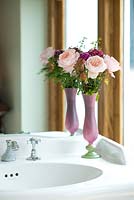 A cut flower arrangement of pink roses in a bathroom