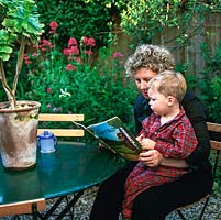 Mhairi Clutson reading a bed time story to her youngest child, Phelin, in their tiny, Mediterranean style back garden with its sunken gravel patio below an enclosed courtyard.