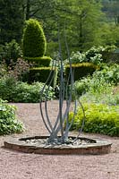 Metal garden sculpture with yew topiary in background. Abbey Dore Gardens, Herefordshire