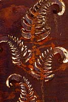 Ornate rusty metal panel with fern leaf providing focal point. At Domaine de Cambou, Verfeil, Haute-Garonne, Midi Pyranees, France.