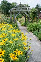 Path through the Lanhydrock Garden, otherwise known as the hot garden, passes below a wooden pergola surrounded by rudbeckias and other choice perennials. Wollerton Old Hall, nr Market Drayton, Shropshire, UK