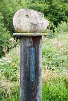 Stone head on wooden plinth. Dyffryn Fernant, Fishguard, Pembrokeshire, Wales, UK