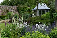 A walled garden with domed summer house and mixed border planted with foxglove, sweet rocket, catmint and alchemilla.