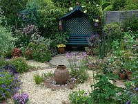 A circular themed gravel garden and patio with cottage garden style planting. Armeria Joystick and a terracotta urn provide a focal point in the centre of the gravel bed. 