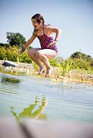 Girl jumping into a swimming pond. 