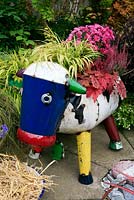 Novelty cow sculpture designed as a planter. Hakonechloa macra 'Aureola' with Heuchera 'Sweet Tea', Calluna vulgaris 'Garden Girls' and dwarf chrysanthemum. 