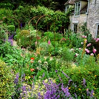 Old stone millhouse has garden of nepeta-lined gravel paths, topiary, Italian cypress, foxglove, eremurus, allium, nectaroscordum, phlomis, peony, delphinium, poppy.