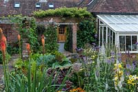 Behind an 1850s coach house conversion, a village garden with mixed beds planted with late flowering  perennials.