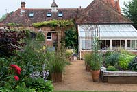A converted coach house with conservatory and wooden raised beds planted with perennials and herbs.
