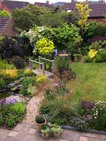 16 metre square back garden with gravel and boggy areas, wildlife pond, bridge, stream, trellis, lawn. Shady and sunny beds - shrubs, alpines, grasses, herbaceous plants.