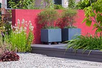 View of terrace with modern geometrical composition of containers and dark red wall