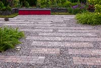 Gravel and brick surface. Dark red bench gives a contrast in general monochromatic set of plant colors